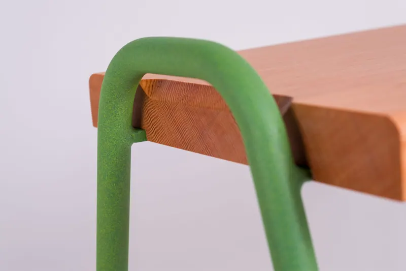 Green powder coated leg meeting the wood seat